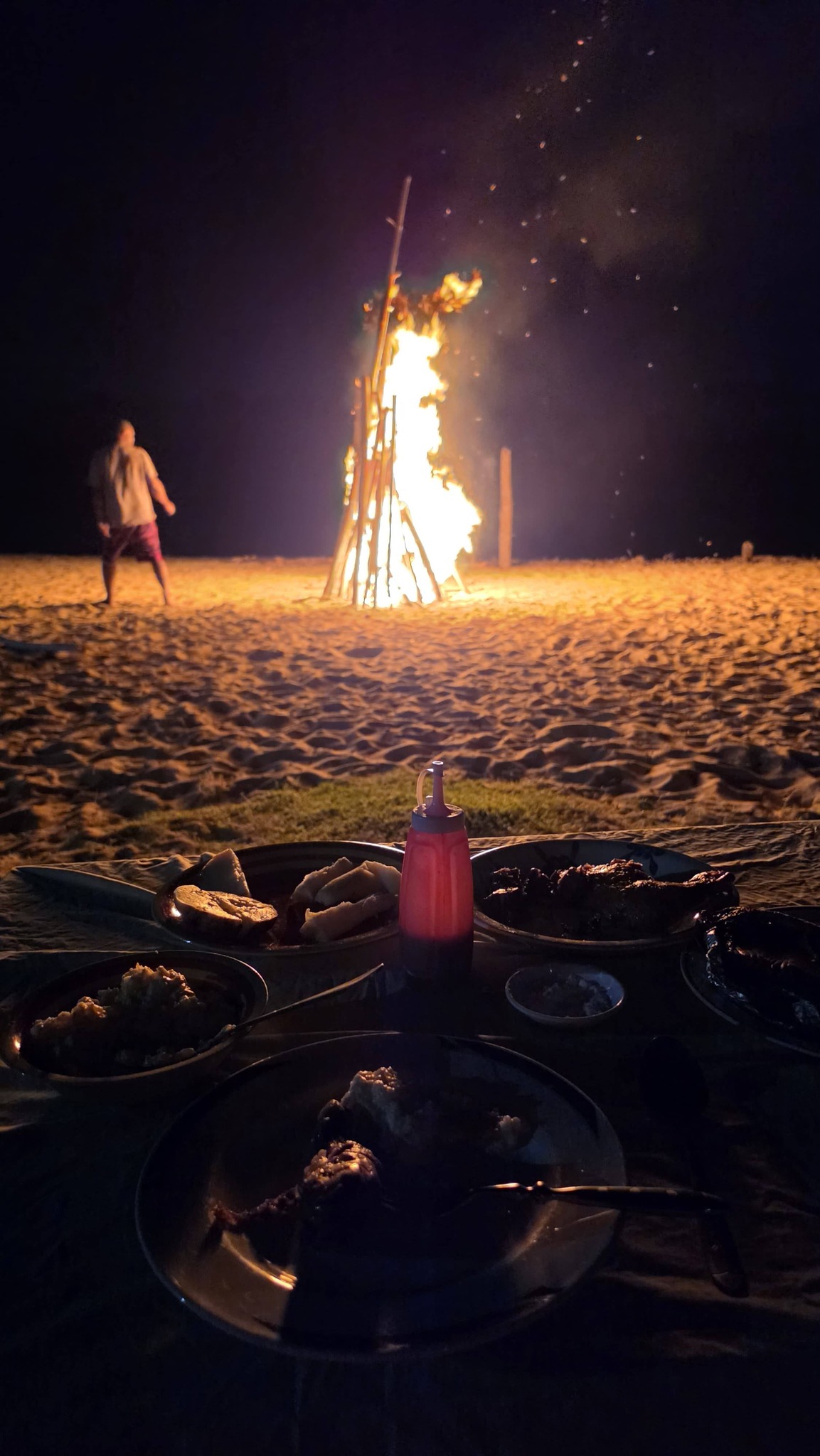 Bonfire on the beach at sunset with glowing embers